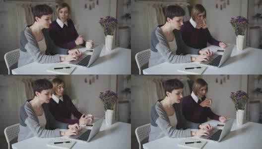 两个女学生坐在桌子旁，用笔记本进行在线教育高清在线视频素材下载