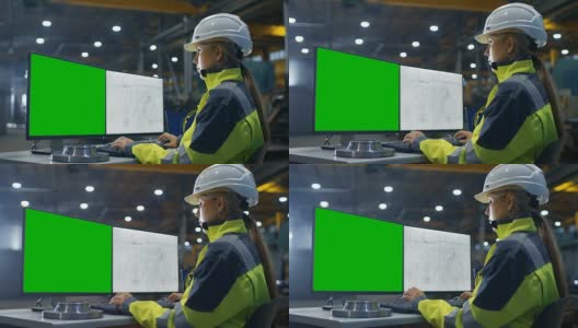 在重工业工厂里，女工业工程师在绿色模拟屏幕的个人电脑上工作。二级监视器显示蓝图。高清在线视频素材下载