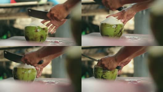 一个男人用一把大刀切开椰子。高清在线视频素材下载