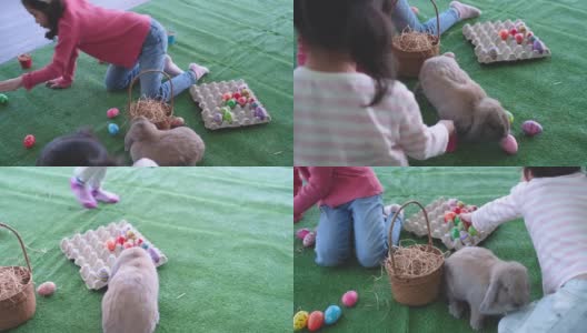 两个亚洲小女孩在客厅里把复活节彩蛋装在镶板上玩，也和棕色的兔子玩得很开心高清在线视频素材下载