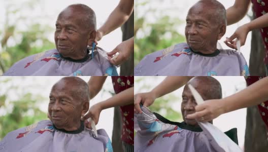 在冠状病毒隔离期间，一名亚洲妇女正在自家后院修剪老人的头发高清在线视频素材下载