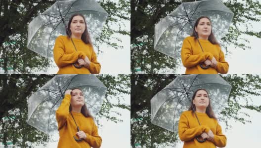 下雨天，一个穿着芥末色毛衣的悲伤女人站在一把透明的伞下冻住了高清在线视频素材下载