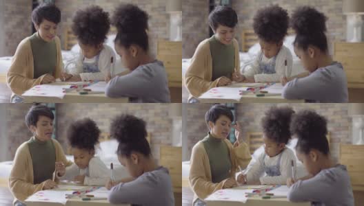 亚洲母亲帮助她的两个非洲女儿和教绘画作业在公寓高清在线视频素材下载