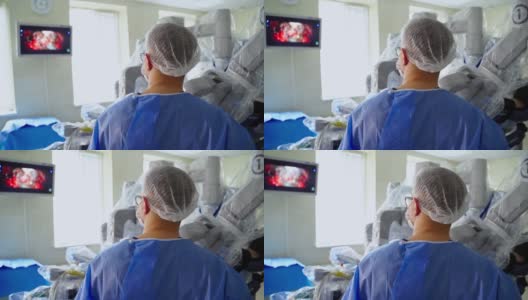 医生用外科手术看着监视器。医院里有一个医疗机器人做现代外科手术。后面的观点。高清在线视频素材下载