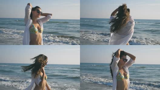 快乐的女人在阳光明媚的海滩上散步和旋转。年轻的女孩戴着太阳镜，微笑着玩弄她的头发。女士在旅行中享受生活。暑假或假期。慢镜头高清在线视频素材下载