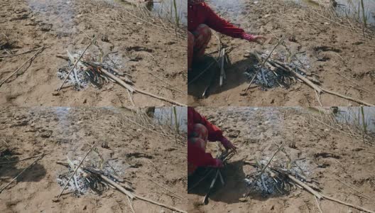 妇女在烤鱼下添加小树枝以保持炉火燃烧高清在线视频素材下载