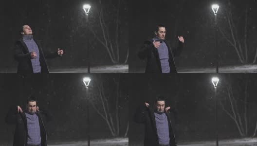 路灯下的那个人。在灯光的映衬下，正在下雪。慢动作，每秒180帧。雪花很漂亮。那个男人穿着一件凉爽的黑外套。高清在线视频素材下载