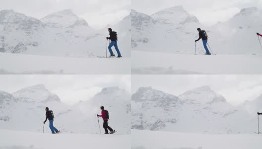 男人和女人沿着雪岭风景走上去。登山滑雪活动。冬季滑雪者在高山户外运动。侧视图。慢动作60p 4k视频高清在线视频素材下载