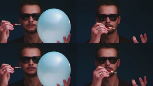 一名戴着太阳镜的欧洲男子用飞镖引爆了蓝色气球高清在线视频素材下载