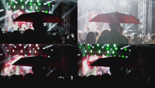 快乐的人们在雨中撑着雨伞观看一场精彩的音乐会高清在线视频素材下载