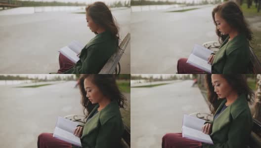 年轻的亚洲女人坐在河边的长凳上看书高清在线视频素材下载