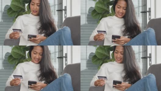 年轻的亚洲女性用智能手机和信用卡支付网上购物，坐在家里的沙发上。数字时代的生活方式高清在线视频素材下载