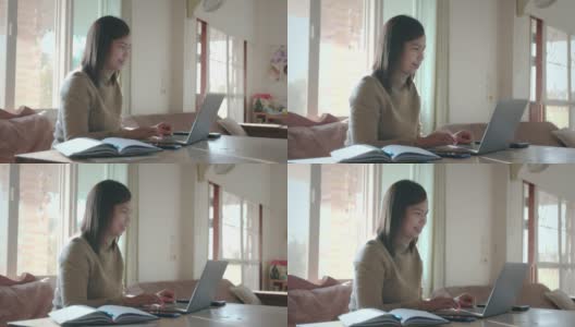 在家工作的女性员工。年轻的亚洲女人在电脑上滚动。她收到来自笔记本电脑的信息，并微笑着阅读信息。高清在线视频素材下载
