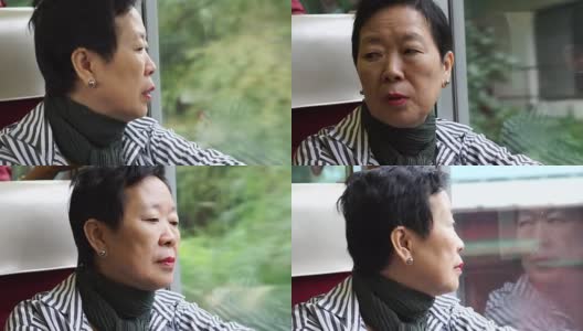 年长的亚裔妇女坐在火车上，透过窗户向外看。在退休旅行中思考和享受风景高清在线视频素材下载