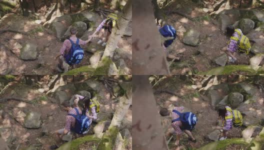 一个男人帮助一个女人爬陡峭的小路。在森林里徒步旅行高清在线视频素材下载