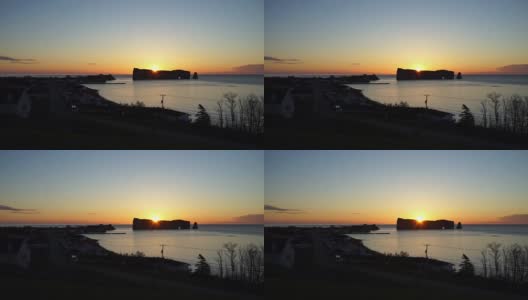 著名的Rocher Perce岩石在加斯皮半岛，魁北克省，加斯皮西地区与城市景观在多彩的日出和光线，太阳躲在后面，升起高清在线视频素材下载