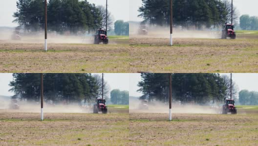 两辆红色拖拉机在炎热干燥的天气下对着电力线柱处理土壤高清在线视频素材下载