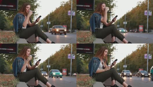 年轻漂亮的女人坐在人行道上喝着咖啡，拿着手机找出租车高清在线视频素材下载