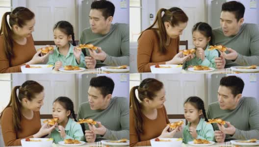 幸福的亚洲家庭，父母和可爱的小女儿早上在家里的厨房吃披萨。周末活动快乐家庭生活理念。呆在家里。庆祝你家庭的大日子。高清在线视频素材下载