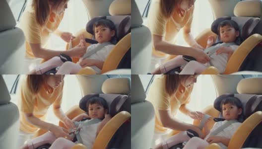 快乐快乐的亚洲家庭妈妈和蹒跚学步的女孩在车里准备出行前系好儿童汽车座椅安全带。高清在线视频素材下载