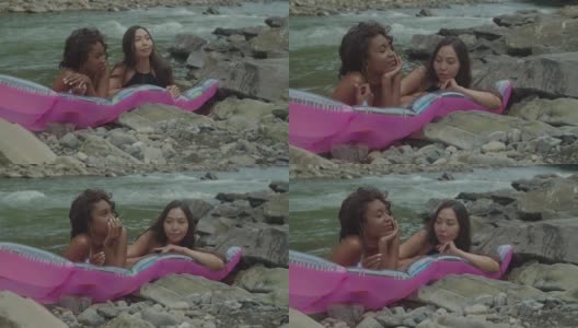 开朗可爱的多种族女性放松在充气床垫在山区河流高清在线视频素材下载