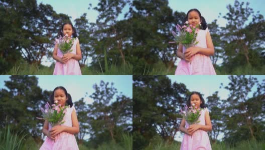 快乐的小女孩带着一束鲜花走过鲜花草地。快乐的小女孩在大自然中梦想。幸福的家庭,日落高清在线视频素材下载