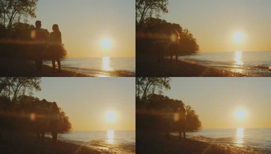 后视图-年轻夫妇沿着海滨散步在日落高清在线视频素材下载