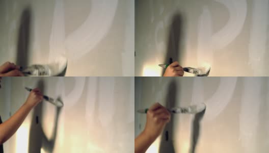 在墙上画着白色字母的女人，慢镜头高清在线视频素材下载