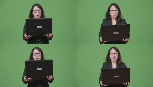 成熟美丽的亚洲商人在绿色背景下使用笔记本电脑高清在线视频素材下载