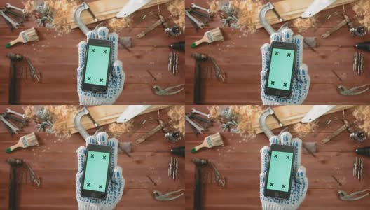 俯视图工匠手握绿色屏幕的智能手机手套高清在线视频素材下载