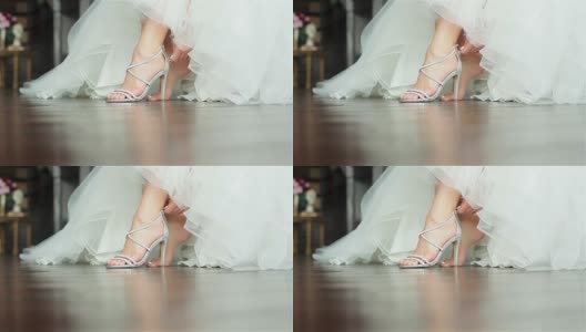 女人穿上鞋，双手合上浅浅的景深。新娘在豪华高跟鞋上系上拉链坐在华丽的白色礼服准备在婚礼上跳舞高清在线视频素材下载