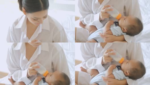 年轻的亚洲母亲在家用奶瓶喂男婴。高清在线视频素材下载