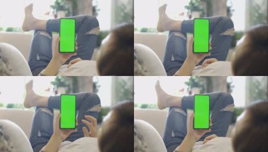 女人在沙发上用绿色屏幕的智能手机高清在线视频素材下载