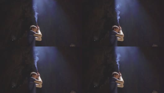 慢镜头拍摄的一个年轻的欧洲男子正在祈祷，手里拿着烟熏香棒。他是在大理石山中最大的石窟寺庙，一个佛教寺庙的综合体高清在线视频素材下载