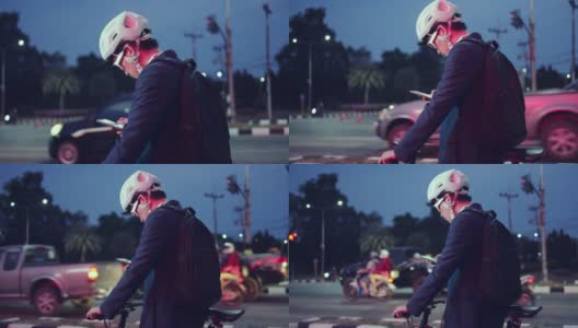 晚上下班后骑自行车回来的亚洲男人。他在红绿灯前停了下来，打了个电话高清在线视频素材下载