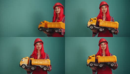 一个戴着施工头盔的快乐女孩手里拿着一辆大卡车高清在线视频素材下载
