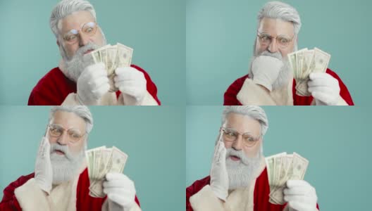 有趣的时尚圣诞老人在蓝色背景与金钱摆姿势。金融、钱,钞票。特写镜头高清在线视频素材下载