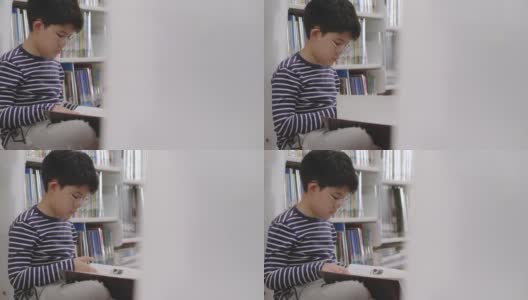 亚洲男孩坐在图书馆看书高清在线视频素材下载