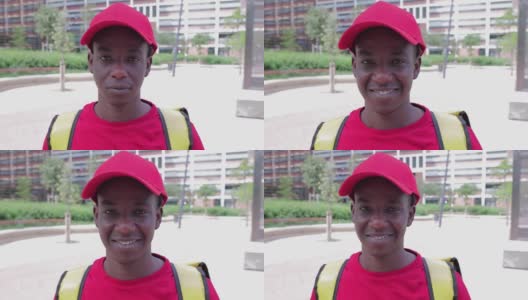非洲裔美国送货员戴着红帽子，穿着t恤，对着镜头微笑高清在线视频素材下载