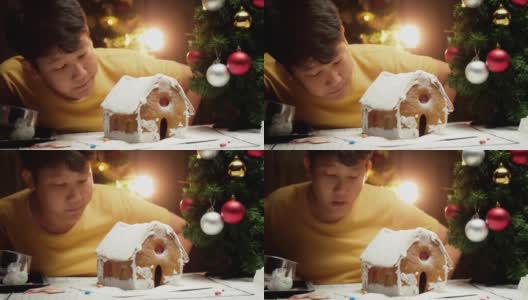 亚洲男孩看着DIY姜饼屋完成后，圣诞节庆祝的生活理念。高清在线视频素材下载