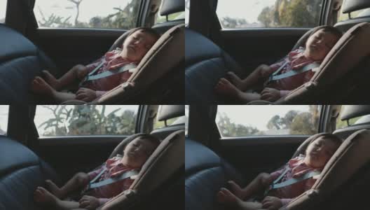 可爱的亚洲蹒跚学步的小女孩坐在汽车座椅上，和家人一起旅行时睡觉。高清在线视频素材下载