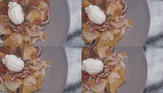 一盘新鲜的墨西哥玉米片，配上洋葱、番茄、墨西哥胡椒、奶酪和酱汁。传统的墨西哥开胃小吃高清在线视频素材下载