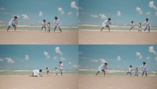 亚洲爸爸和妈妈在夏天的海滩上和孩子玩拔河游戏。父母和孩子们去海边度假。幸福的家庭关系和团队合作理念。慢动作镜头高清在线视频素材下载