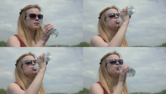 描绘了一个年轻女子在炎热的夏天喝着塑料瓶里的冷水高清在线视频素材下载
