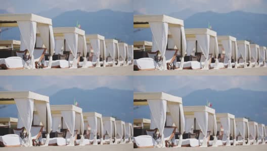 在傍晚的阳光下，绿松石大海前的木制日光浴床。在著名的意大利海滩Forte dei Marmi日光浴床高清在线视频素材下载