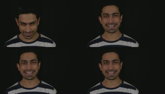 一名年轻的印度男子的肖像面朝上，露出牙齿，直视着黑色背景的相机高清在线视频素材下载