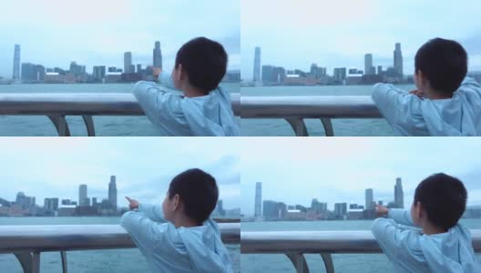 可爱的男孩指着香港的摩天大楼高清在线视频素材下载