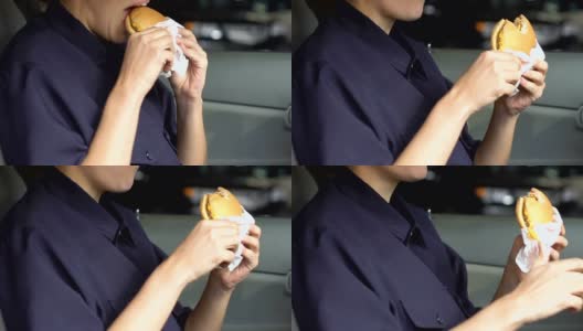 在车里吃油腻汉堡的女巡警，饥饿的警察，不健康的食物高清在线视频素材下载