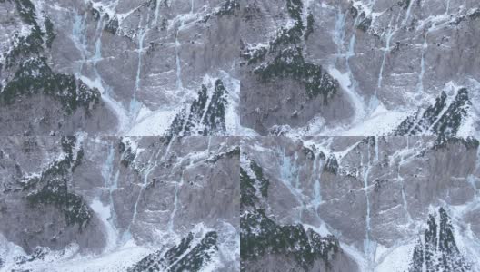 AERIAL:冰冻的河流从斯洛文尼亚一座雪山的悬崖上倾泻而下。高清在线视频素材下载