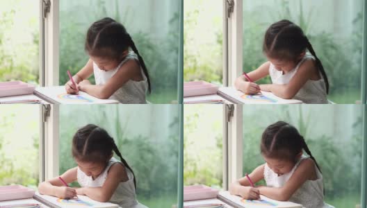 在冠状病毒隔离期间，快乐的亚洲儿童学生或女童使用绘彩铅笔，享受在白纸上写字的乐趣。待在家里，保持社交距离，保护冠状病毒肺炎封锁和学校关闭。高清在线视频素材下载